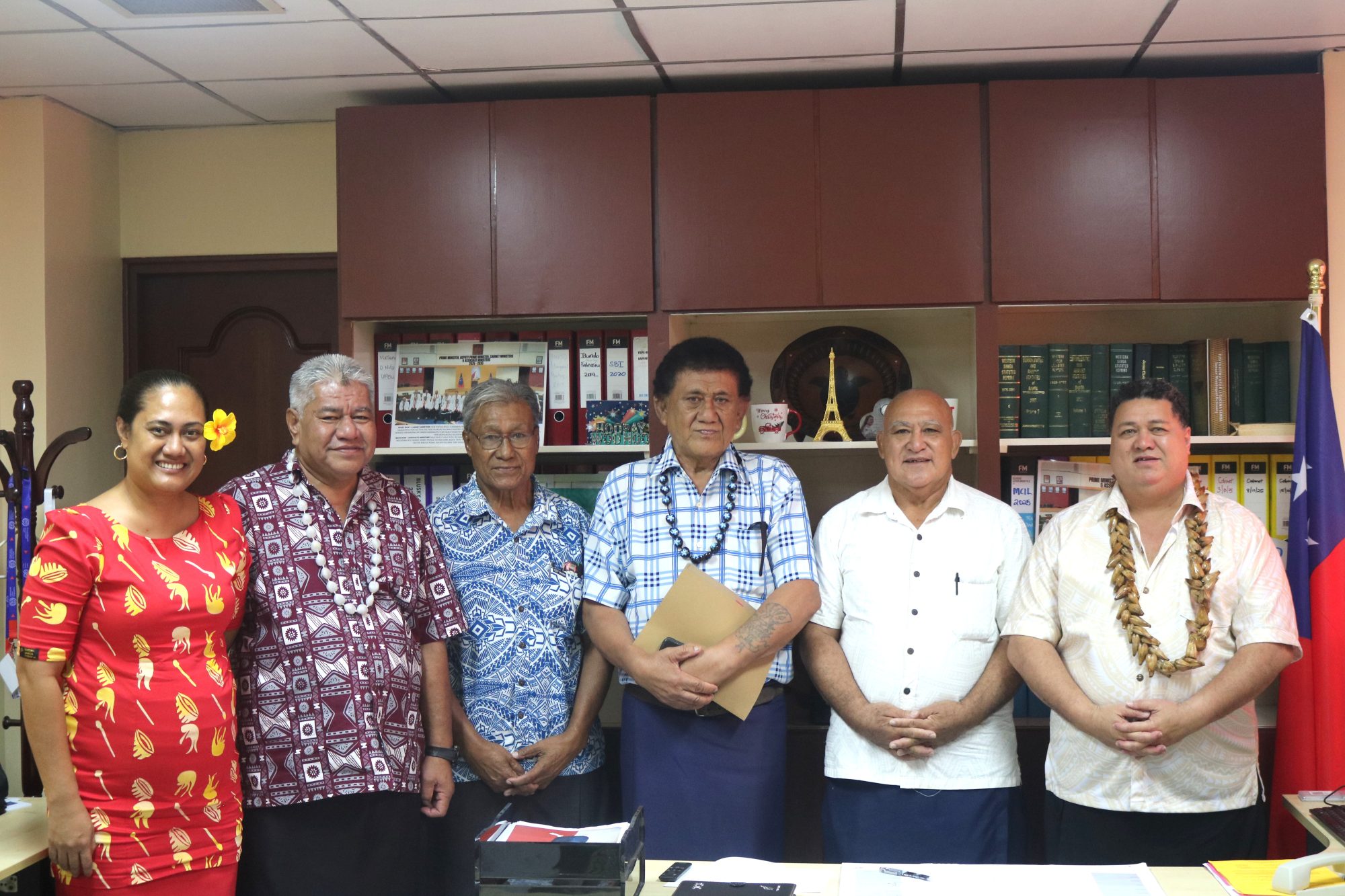 The newly appointed Commissioners of the Samoa Competition and Consumer Commission with the Honourable Minister for Commerce, Industry and Labour, beside the national flag of Samoa.