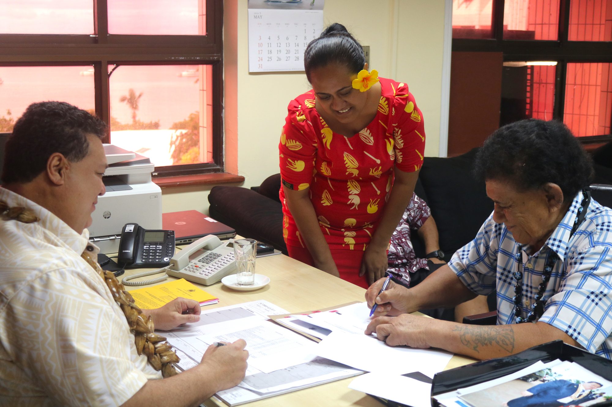 A newly appointed Commissioner signing his contract at the Ministry of Commerce, Industry and Labour, assisted by a ministry officer.