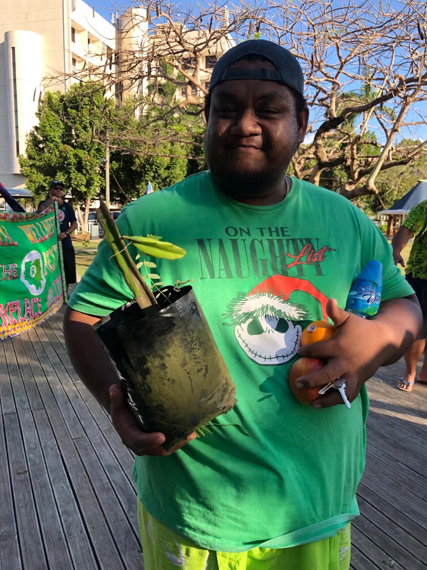 A participant holds a tree seedling at the Mental Health Awareness Walk